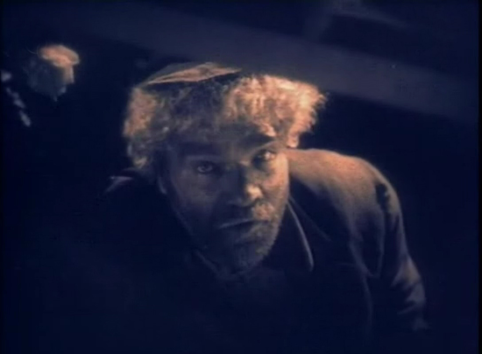  Kadr z amerykańskiego filmu „Chciwość” z 1924 roku. Widać na nim mężczyznę patrzącego w górę. Mężczyzna ma jasne, kręcone włosy i zarost. 